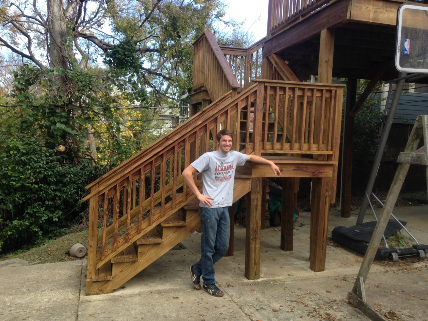 A man standing next to a wooden staircase.