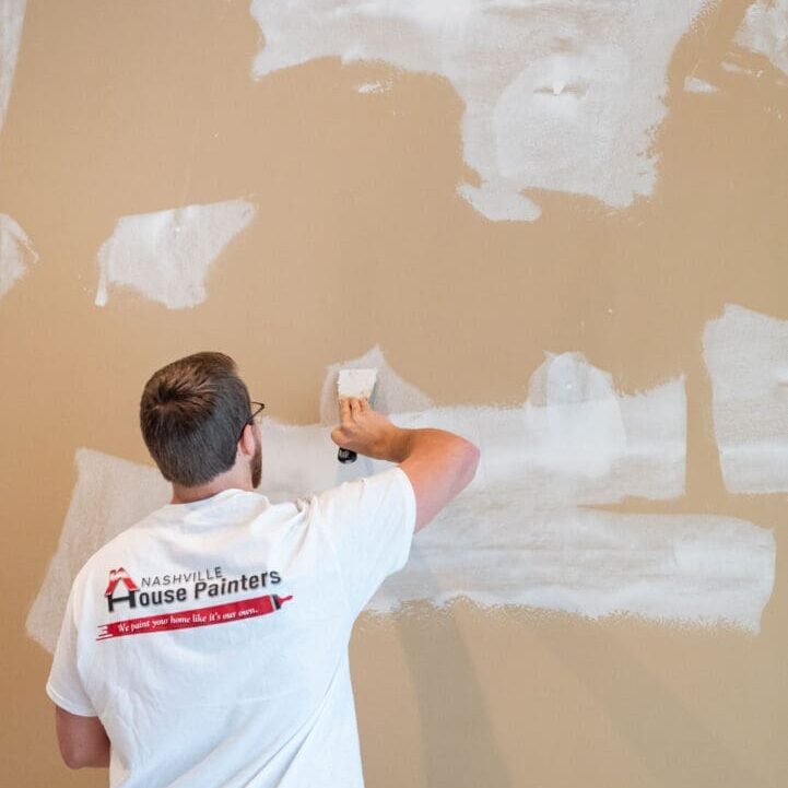 A man in white shirt painting the wall.